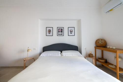 a bedroom with a large white bed with three pictures on the wall at Minimà Peschici in Peschici
