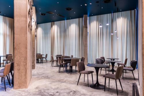 um restaurante com mesas e cadeiras e janelas grandes em Nova Concierge Hotel em Batumi