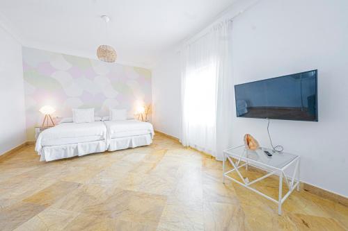 a white bedroom with two beds and a flat screen tv at Labreña Hotel in Los Caños de Meca