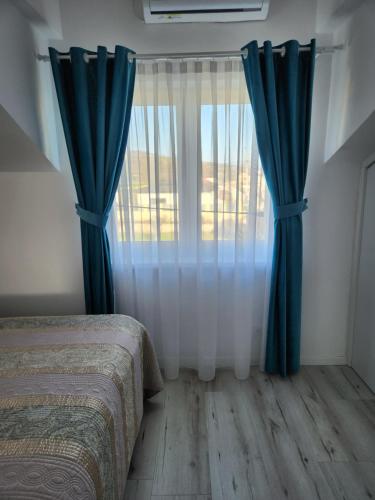a bedroom with a bed and a window with blue curtains at Vila Reghina in Alba Iulia