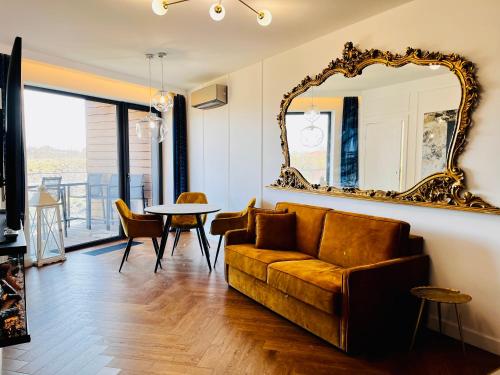 a living room with a couch and a mirror at Pratum Pink&Blue Mikołajki Apartament de lux z kominkiem, prywatnym pomostem i 400m strefą wellness in Mikołajki