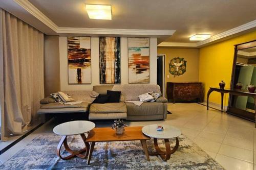 a living room with a couch and two tables at Luxo e conforto à beira-mar em canto nobre da praia in Guarapari