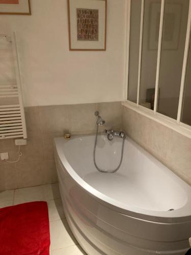 La salle de bains est pourvue d'une baignoire blanche et d'un tapis rouge. dans l'établissement Tour Eiffel - Grand deux pièces avec terrasse, à Paris