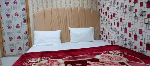 Una cama con dos almohadas y flores. en H-J Family Hotel en Lahore