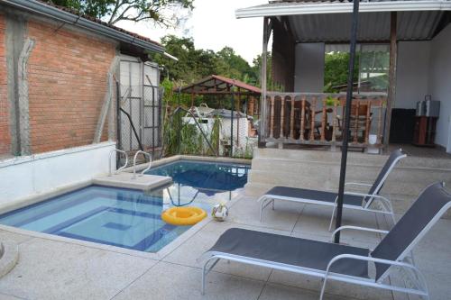 einen Pool mit 2 Stühlen und einem Sonnenschirm in der Unterkunft Casa Verde Chalet in La Tebaida