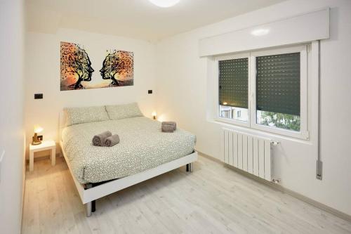 een witte slaapkamer met een bed en een raam bij Appartamento Moderno per 6 Aviano A/C Parking in Aviano