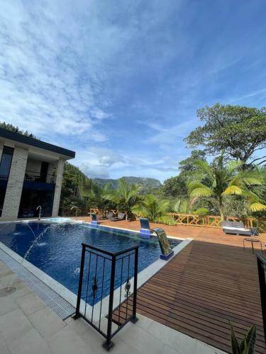 a pool with a wooden deck next to a house at Home Boutique Natural Paradise in La Vega