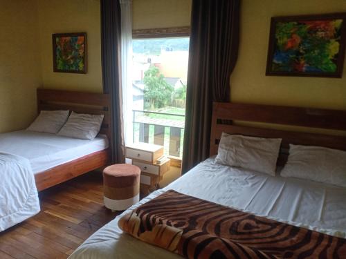2 camas en una habitación con ventana en Homestay ANEMON en Dieng
