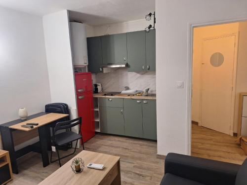 une cuisine avec des armoires vertes, une table et des chaises dans l'établissement Golfe-Juan port, à Vallauris