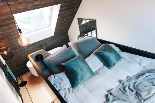 een slaapkamer met een bed met blauwe kussens en een raam bij demimaisons in Esneux