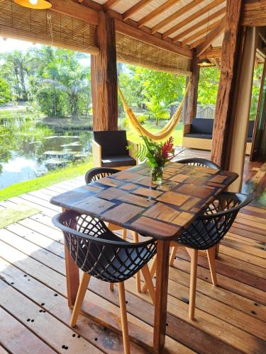 バーハ・グランデにあるWoodstock Bungalow - Barra Grande - condo frente praiaの木製テーブルと椅子付きのポーチ(ハンモック付)