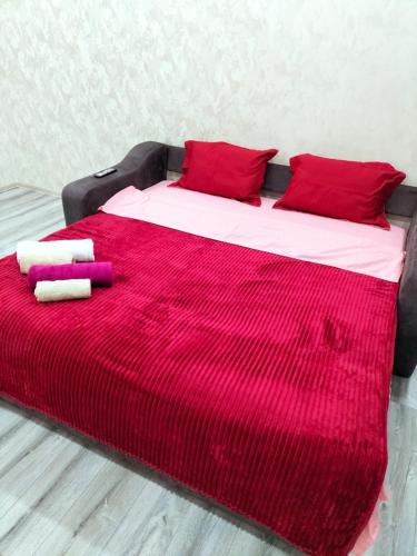 a bed with red and white sheets and red pillows at Новые апартаменты в центре города Кокшетау in Kokshetau