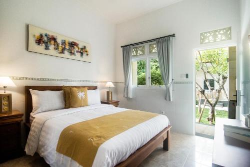 a bedroom with a large bed and a window at The Cozy Haven Sanur in Sanur