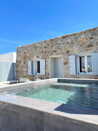 a swimming pool in front of a stone house at Sea Wind Villas and Suites in Tourlos
