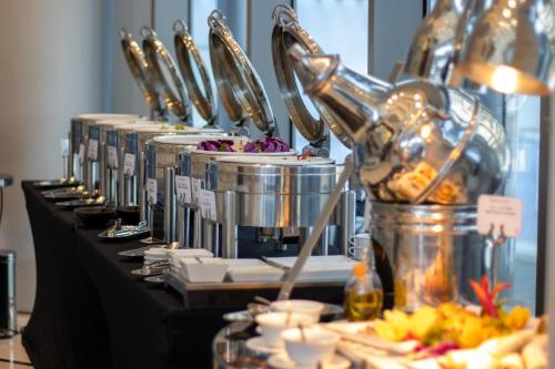 a row of pots and pans on a table with food at Somerset Downtown Al Khobar in Al Khobar