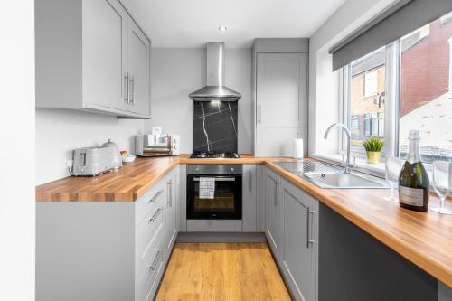 a kitchen with white cabinets and a wooden counter top at Modern 2 Bedroom Apartment - Off-street Parking - Top Rated - 1aS 