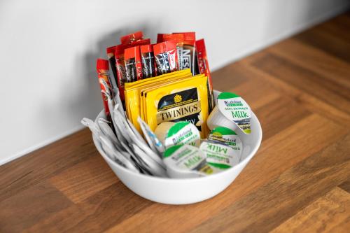 a white bowl filled with packets of candy at Modern 2 Bedroom Apartment - Off-street Parking - Top Rated - 1aS in Amblecote