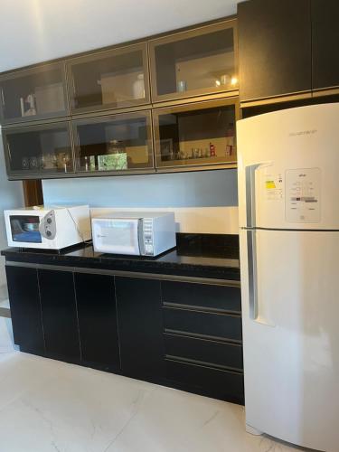eine Küche mit schwarzen Schränken und einem weißen Kühlschrank in der Unterkunft Estadia Barragem do Salto - Casa Mugam in São Francisco de Paula