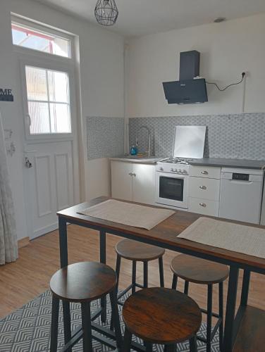 una cocina con mesa y taburetes. en Maison EL Marielle, en Vierzon