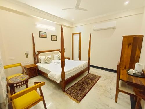 ein Schlafzimmer mit einem Bett, einem Stuhl und einem Schreibtisch in der Unterkunft Gupta Vilas - A Boutique Homestay in Agra