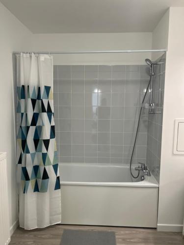 La salle de bains est pourvue d'une baignoire avec rideau de douche. dans l'établissement Superbe 3 pièces avec balcon pour 5 personnes, à Villiers-le-Bel