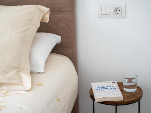 a bed with a glass of water and a book on a table at Apartment Abora with Pool, Gym and Free Parking in Las Palmas de Gran Canaria