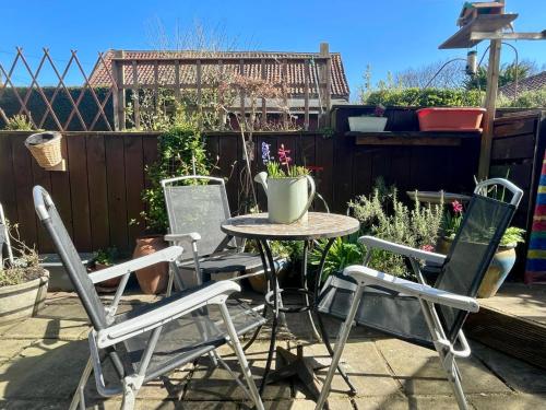 a patio with a table and chairs in a garden at May Rose Cottage in Sigglesthorne
