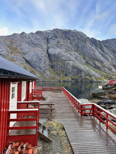 a wooden dock with a building next to a mountain at Nusfjord Waterfront Rorbu 18 in Ramberg
