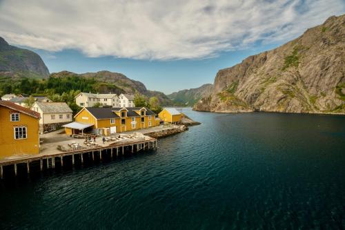 un pueblo en un cuerpo de agua con montañas en Nusfjord Waterfront Rorbu 18, en Ramberg