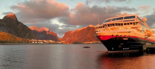 a large boat is docked in the water with mountains at Nusfjord Waterfront Rorbu 18 in Ramberg