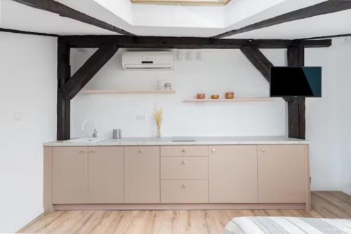 a kitchen with white cabinets and a tv on the wall at Wiślna Old Town Apartments in Krakow
