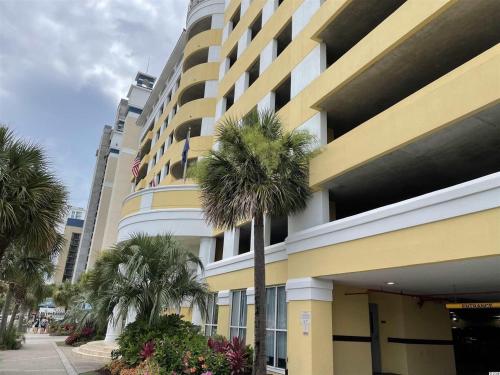 a large building with palm trees in front of it at Camelot By The Sea - Blue Palmetto Vacation Rentals in Myrtle Beach
