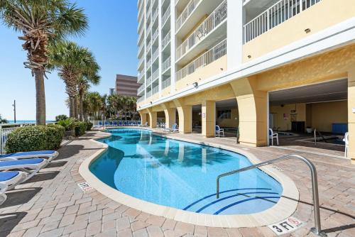 a swimming pool at the resort with chairs and palm trees at Camelot By The Sea - Blue Palmetto Vacation Rentals in Myrtle Beach