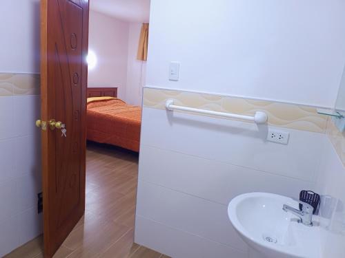 baño con lavabo y cama en LOS NEVADOS II en Huaraz