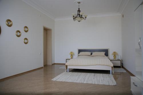 a white bedroom with a bed and a chandelier at Exciting seaview villa Aymesa in Baku