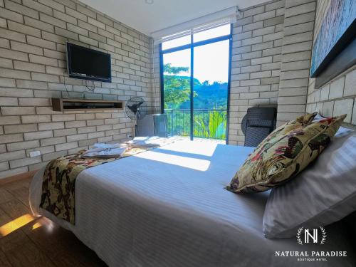 a bedroom with a large bed with a tv on a brick wall at Home Boutique Natural Paradise in La Vega
