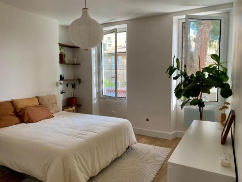 een witte slaapkamer met een bed en een potplant bij T4 rénové, clim, internet & Netflix, tout confort in Marseille