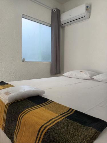 a bedroom with a large white bed with a window at Pousada Bsm in Barra de São Miguel