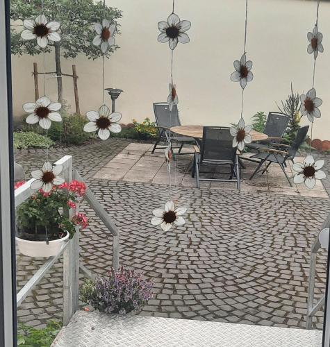 a patio with a table and chairs and flowers at Bauernhaus Schunck im Bliesgau in Blieskastel