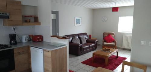 a kitchen and a living room with a leather couch at Le Petit Lac in Bourganeuf