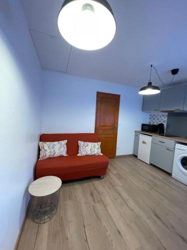 a living room with a red couch and a kitchen at Appartement proche des thermes d'Allevard les Bains in Saint-Pierre-dʼAllevard