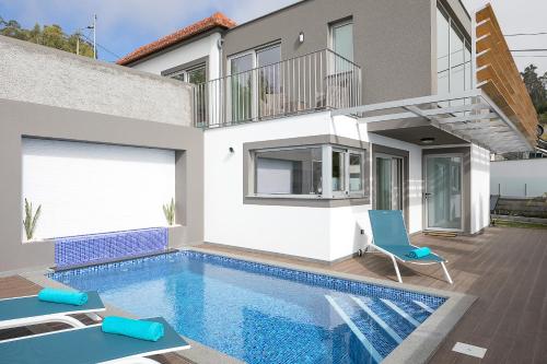 a house with a swimming pool in front of a house at Bella Vista (Heated Pool & Private Parking) in Arco da Calheta