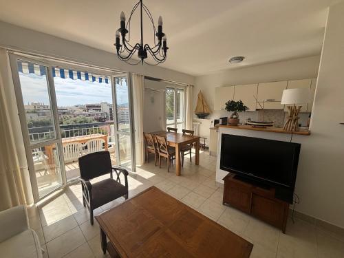 un salon avec une télévision à écran plat et une table dans l'établissement 2 pièces 500 m de la mer, à Antibes