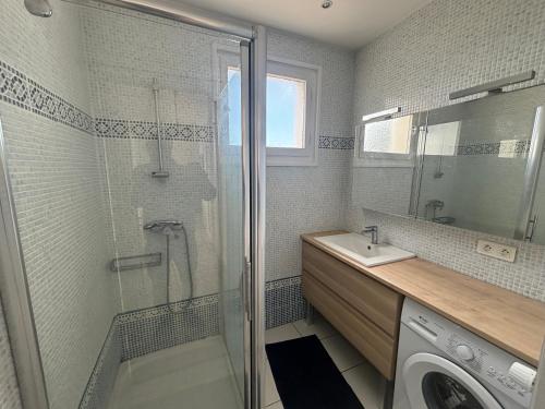 uma casa de banho com um chuveiro, um lavatório e uma máquina de lavar roupa em 2 pièces 500 m de la mer em Antibes
