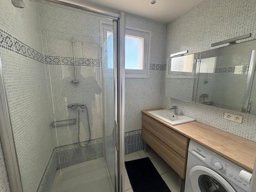 une salle de bain avec douche et lavabo et une machine à laver dans l'établissement 2 pièces 500 m de la mer, à Antibes
