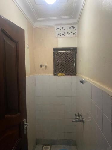 a bathroom with a tiled shower with a window at PiperZ in Entebbe