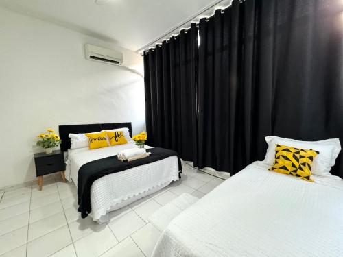 1 dormitorio con 2 camas, cortinas negras y almohadas amarillas en Apartamento Copa Home HIR 3, en Río de Janeiro