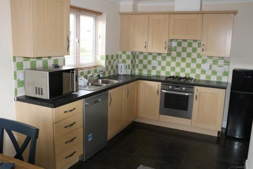 een keuken met een wastafel en een magnetron bij The Iris house is close to city centre and is ideal for tourists, visiting family members or work related activities including contractors in Peterborough