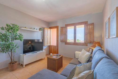 Una sala de estar con un sofá azul y un televisor en El Mirador de Emma, en Los Cancajos