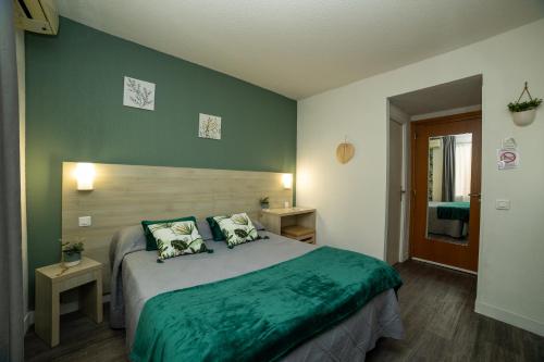 a bedroom with a large bed with green sheets at Hotel Parisien in Menton